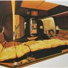 Sleeping Format - This is the rear lounge — and that bed, gentlemen, measures seven feet by six feet. In the center, below the TV and the movie projector (a screen rolls down over the rear window, foreground), is the bar capsule; it's lined with crushed velvet, like the phone container to its right.