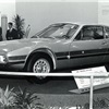 A low and dynamically designed sports coupé that hugs the ground, with large wheels, a long front and distinctive double headlights.