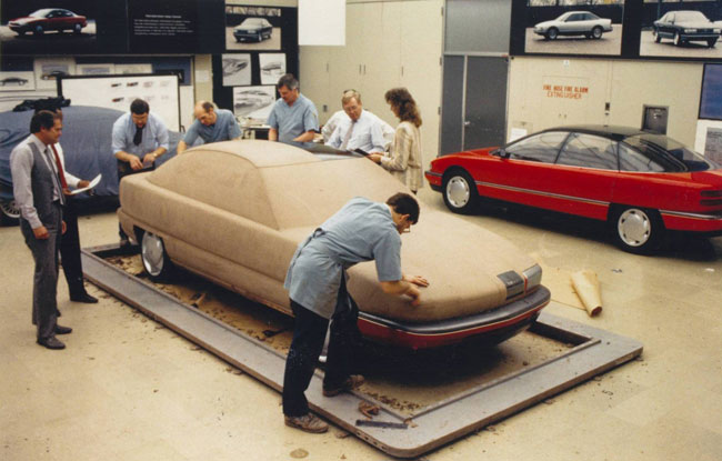 Studio photos showing the fiberglass model in the background, as development progresses productionizing the design.
