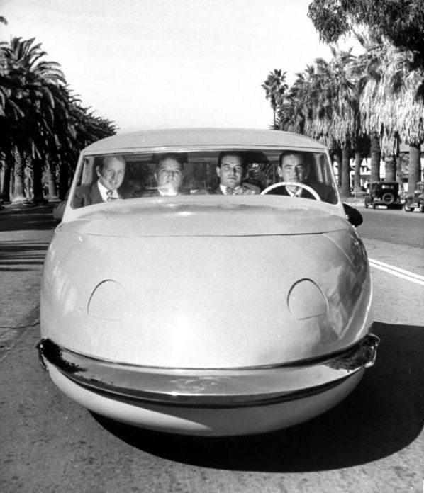 Four men driving down street in Davis Motorcar three-wheeled car, Los Angeles, CA, US. (1947). Photographer: Allan Grant