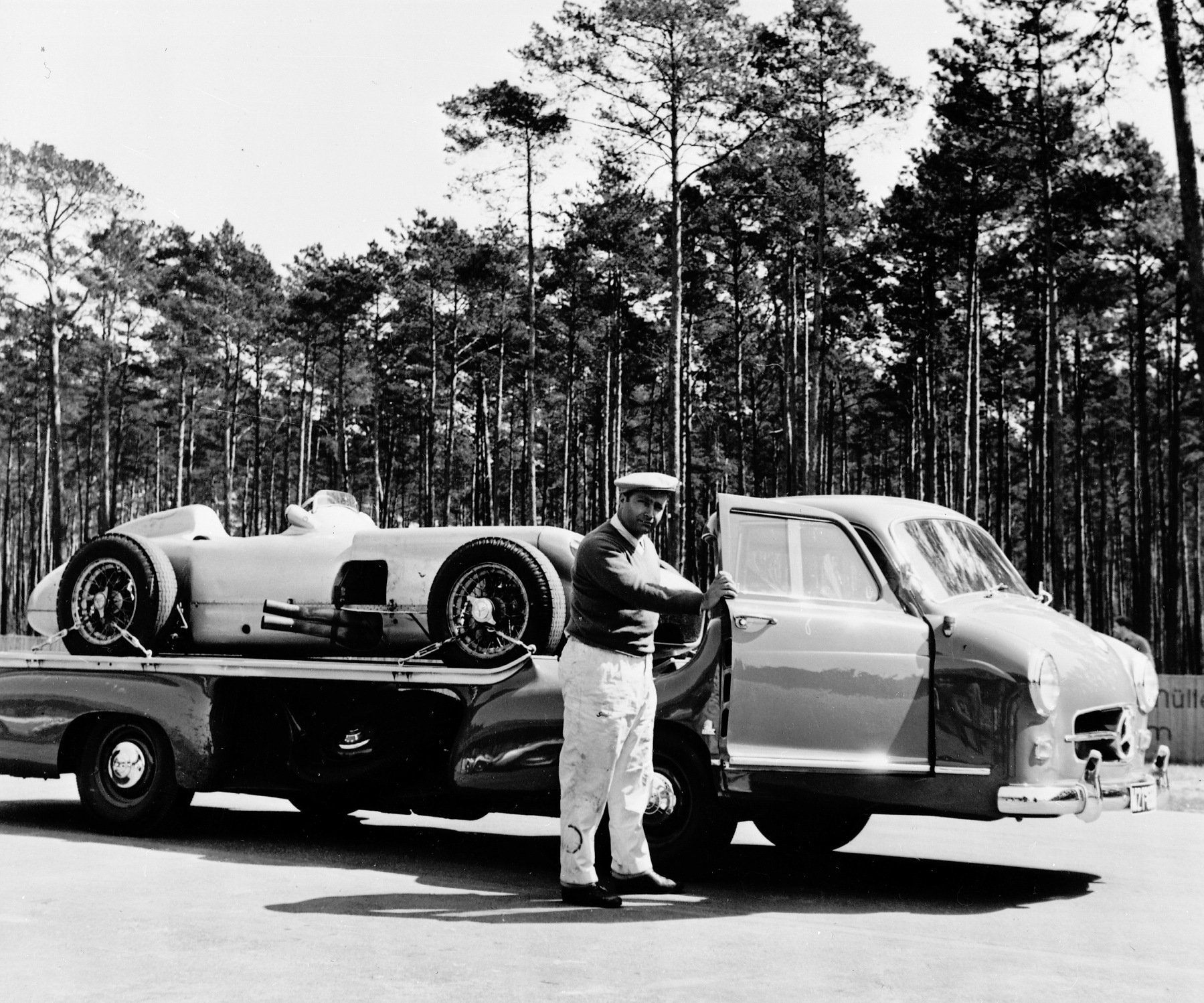 Test driving at Hockenheimring in 1955. The multiple world champion Juan Manuel Fangio and “The Blue Wonder” racing car carrier from Mercedes-Benz with a W 196 R Formula 1 racing car on its loading platform.
